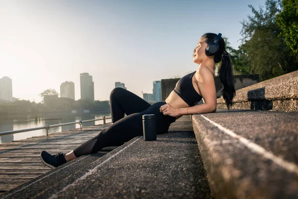 Mujer asiática relajándose después del entrenamiento durante el amanecer — Foto de Stock