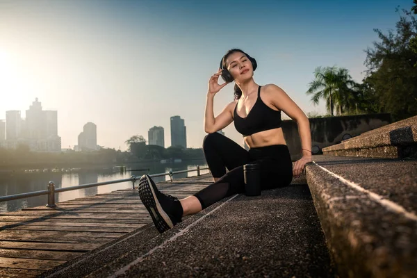 Mujer asiática escuchando música y relajándose después del entrenamiento — Foto de Stock