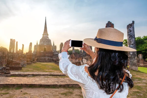 Woman taking a photo with a phone in touristic asian place