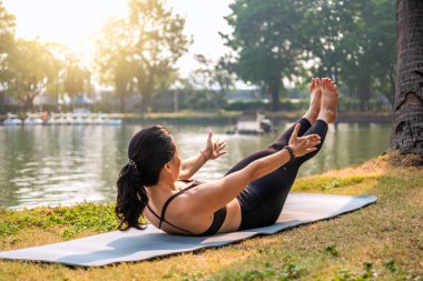 Karın kasları ve karın kasları eğiten kadın. Bir gölün önünde yoga eğitimi.