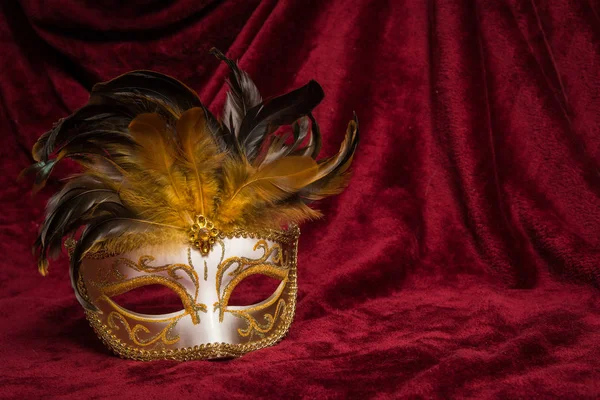 Masque de carnaval vénitien doré marron sur un rideau de velours rouge drapé — Photo