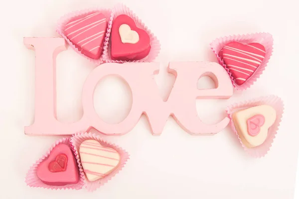 Петрушки в форме розового сердца, видимые сверху, украшены розовыми буквами, говорящими о любви на белом фоне — стоковое фото