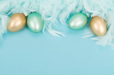 Dekorasyon Cam sarı ve yeşil Paskalya yumurtaları ve metin için yer ile mavi bir arka plan üzerinde mavi tüyleri