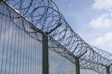 Mavi bir gökyüzü bulutlu barbwired çit