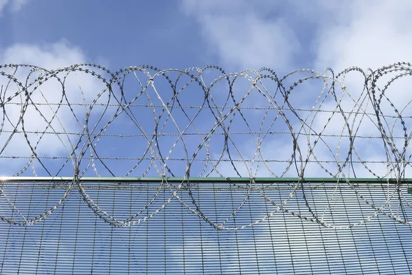 Straight part of a barbwired fence on a blue sky with clouds — Stock Photo, Image