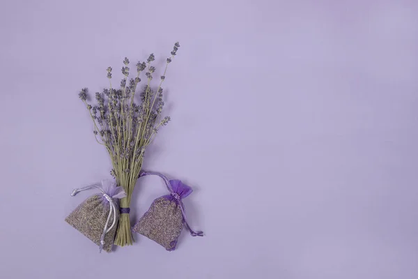 Lot de fleurs de lavande séchées et sachets de lavande sur fond de couleur lavande — Photo