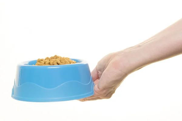 Tazón de alimentación de plástico azul con la mano femenina llena de kibble de gato — Foto de Stock