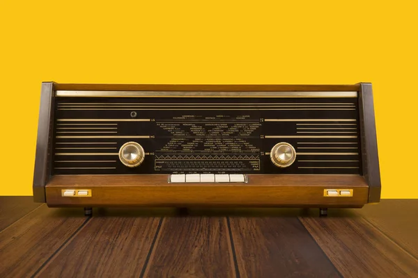 Antigua radio antigua sobre fondo amarillo con mesa de madera marrón oscuro — Foto de Stock