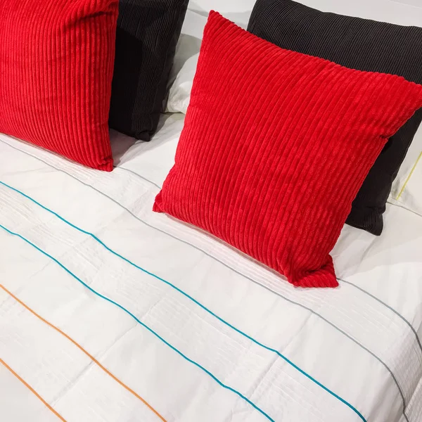 Bed with red and black velveteen cushions — Stock Photo, Image