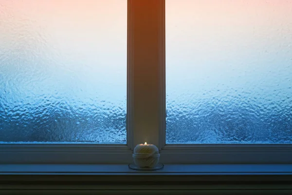 Frostat kvälls fönster med en ljus bränning — Stockfoto