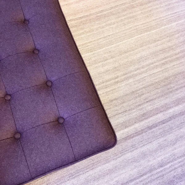Пурпурный оттоман на полосатом ковре — стоковое фото