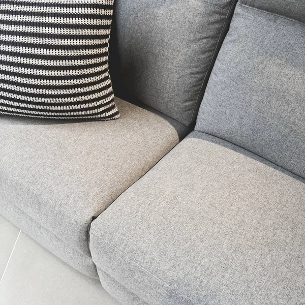Coussin rayé décorant un canapé textile gris — Photo