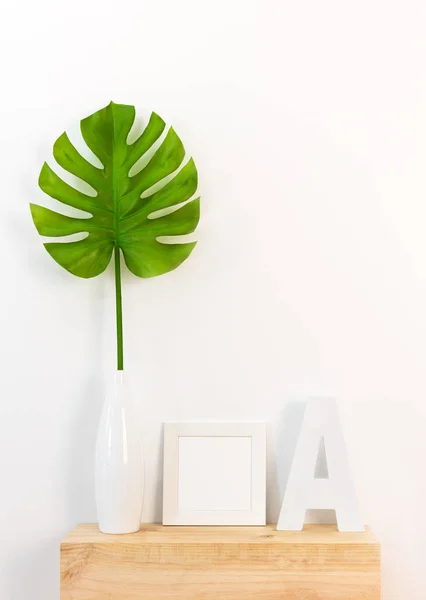 Elegant home decor with picture frame and tropical leaf — Stock Photo, Image