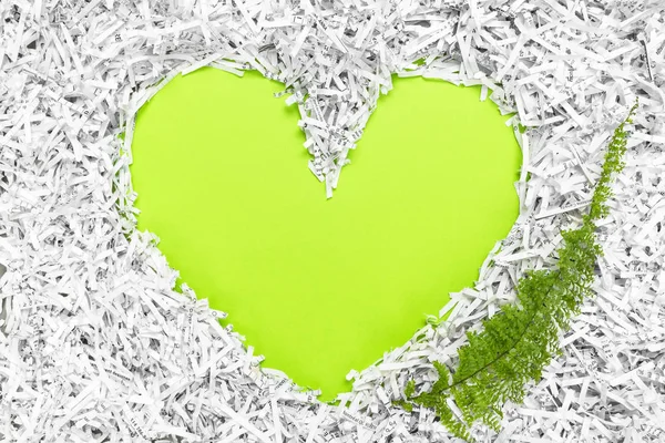 Heart frame made of shredded paper and a green leaf — Stock Photo, Image