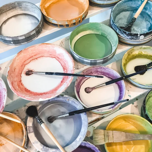 Paint brushes in colorful ceramic plates — 스톡 사진