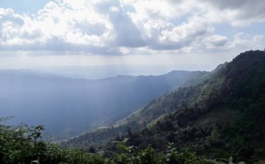 Dağların içine Bulutların arasından Güneş'ten ışık.