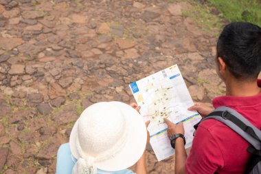Erkekler ve yaşlı kadınlar güzergahı incelemek için haritayı inceliyorlar. Kumtaşı Kalesi, Phanomrung Tarihi Park Buriram, Tayland.