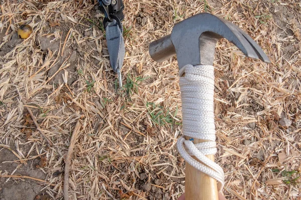 Hammer putting a nail-like tent peg out of iron into the grass on the ground. Push the anchor of the tent onto the ground.Travel concept.