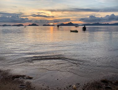 El Nido, Filipinler - 30 Ekim 2019: Sahildeki teknelerin gün batımı silueti.