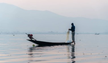 Nyaungshwe, Myanmar: 12 Mart 2020 - Balıkçı gün doğumunda ağ ile balık tutar.