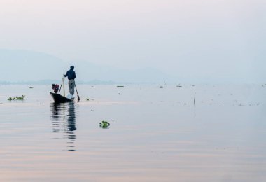 Nyaungshwe, Myanmar: 12 Mart 2020 - Balıkçı gün doğumunda ağ ile balık tutar.
