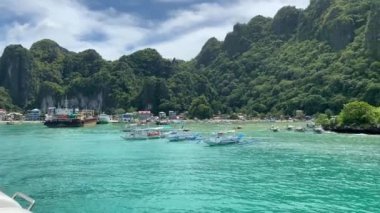 El Nido, Palawan, Filipinler: 26 Ekim 2019. Okyanusta yemyeşil karst ve bangka tekneleriyle Coron 'a giden feribotla mavi sulara bakan körfez. UHD H.264