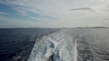 Coron 'dan El Nido' ya giden feribotun güvertesinden yeşil dağ adaları ve derin mavi okyanus suyuyla güçlü su akıntısına bakan tekne motorunun görüntüsü. 30 fps gerçek zamanlı UHD video H.264