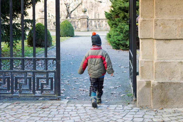 Bambino che cammina attraverso un cancello in un parco o giardino — Foto Stock
