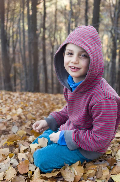 Kind sitzt im Herbst oder Herbst im Wald — Stockfoto