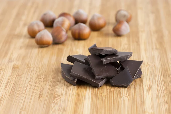 Dunkle Schokolade und Haselnüsse auf dem Tisch — Stockfoto