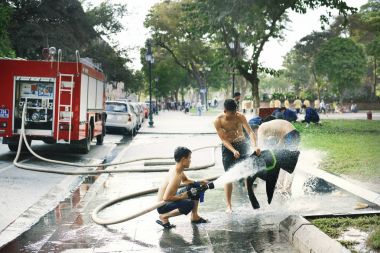adamlar itfaiye su ile oynanan vardır ve Hanoi, Vietnam için elbiselerini yıkamak.