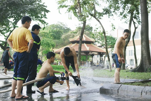 Caras são bombeiros jogado com água e lavar suas roupas em Hanói, Vietnã . — Fotografia de Stock