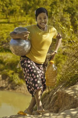 Mrauk U, Myanmar - 1 Aralık 2015: Birmanya gülümseyen gel geri kavanoz Mrauk U yakınlarında küçük bir köyden su ile River