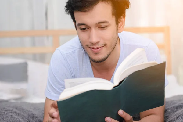 Yakışıklı adam gönüllülük a kitap birlikte yatak odasında. — Stok fotoğraf