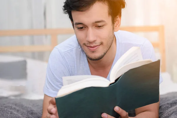 Stilig man läser en bok tillsammans i sovrum. — Stockfoto