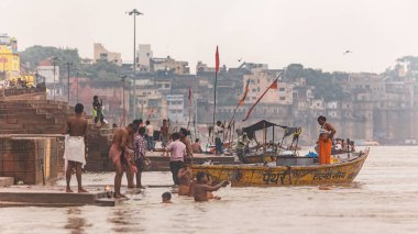 Varanasi, Uttar Pradesh, Hindistan 'daki Ganj (Ganga) nehri boyunca uzanan eski binalarla ghat' ta yaşayan Hintli insanların yüzen tekneleri ve çeşitliliği.