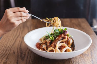 Elle sıkılmış spagetti deniz ürünleri ve çatalla kaldırılan: karidesli spagetti, kalamar, zeytinyağında pişirilmiş midye, biber ve sarımsaklı spagetti.