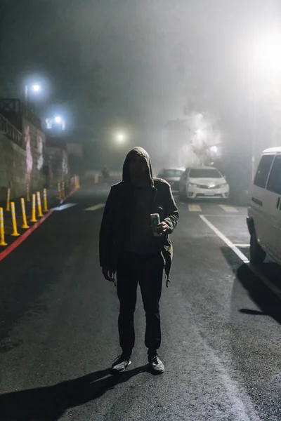 A man wearing hood jacket in the dark and standing still in Alishan National Forest Recreation Area in winter in Chiayi County, Alishan Township, Taiwan.
