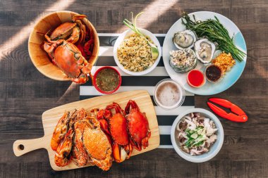 Buğulanmış Dev Çamur Yengeçler, Buğulama Çiçek Yengeçler ve Izgara Karides (Karides) ahşap doğrama tahtası, Yengeç Kızarmış Pilav, Tay Tarzı Taze İstirid ve Tavada Sarımsak Kalamar üst görünümü. 