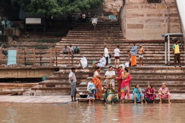 Varanasi, Uttar Pradesh, Hindistan 'daki Ganj (Ganga) nehri boyunca arka planda eski binalar bulunan ghat' ta yaşayan Hintli insanların çeşitliliği.