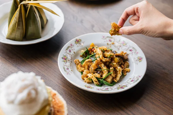 stock image Hand pinching Stir Fried Spicy Crispy Pork Skin with Acaci. Classic Thai cuisine.