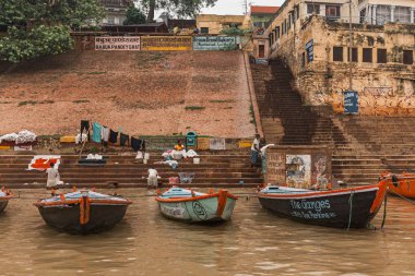 Varanasi, Uttar Pradesh, Hindistan 'daki Ganj (Ganga) nehri boyunca uzanan eski binalarla ghat' ta yaşayan Hintli insanların yüzen tekneleri ve çeşitliliği.