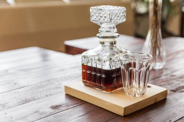 Hot drip coffee in elegant glass bottle with a drinking glass on wooden plate.