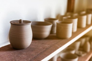 Seramik kupaya yakın çekim, ahşap sergi rafında Lid ile el yapımı seramik kaseler, tabaklar ve fincanlar gibi. Yaratıcı atölye. 
