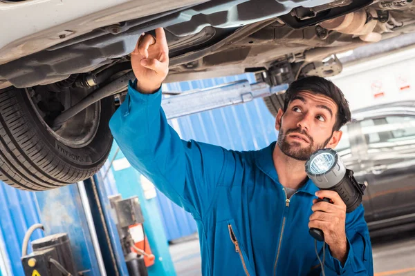 フラッシュライトで車の底を調べる機械 自動車修理サービスセンター 専門職 — ストック写真