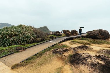 Wooden walkway on landscape of Yehliu Geopark, a cape on the north coast of Taiwan. A landscape of honeycomb and mushroom rocks eroded by the sea. clipart
