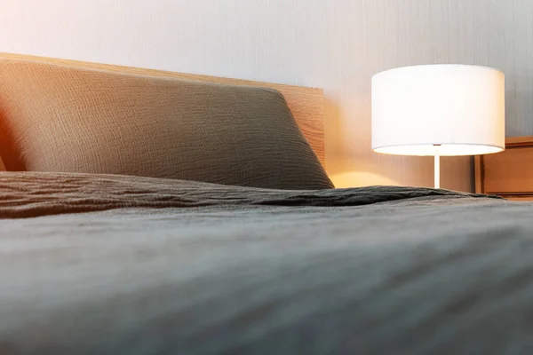 Κρεβάτι Γκρι Κουβέρτα Και Μαξιλάρι Λευκό Ηλεκτρικό Λαμπτήρα Στο Κομοδίνο — Φωτογραφία Αρχείου