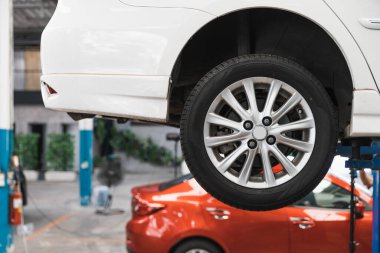 Tamirci tarafından denetlenmeyi bekleyen asansördeki araba. Sağ arka tekere odaklan. Otomobil tamirhanesi, otomobil profesyonel servisi..