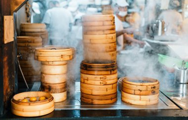 Tayvan 'ın Taipei şehrinde arka planda bulanık şeflerle birlikte restoranın önünde bambu budan yapılmış buharlı tencere yığınları var. Öndeki bambu bularına odaklan..