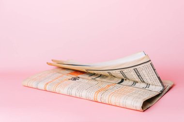 Pembe arka planda eski gazetelerin katlanması. Modern çağ konseptinde eski haberler. 